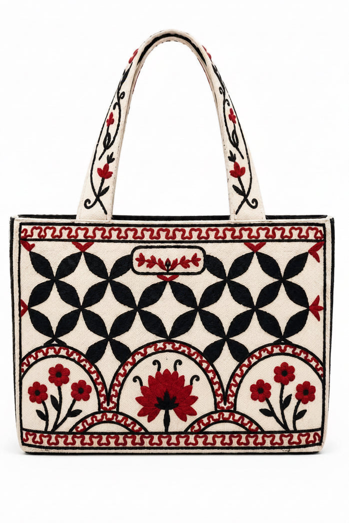 A striking handcrafted tote featuring intricate red and black floral embroidery against a warm natural background. The bold geometric pattern and beautifully embroidered handles give this bag a timeless, artisan-inspired character.
Spacious and eye-catching, it’s perfect for work, shopping, books, everyday essentials, or as a thoughtful gift. The detailed craftsmanship makes each piece feel special while still being practical enough for everyday use.