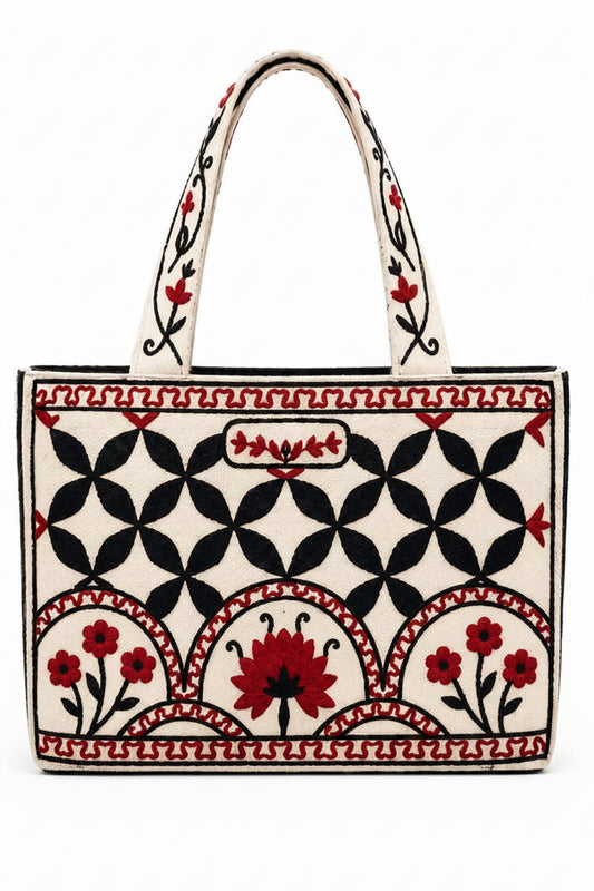 A striking handcrafted tote featuring intricate red and black floral embroidery against a warm natural background. The bold geometric pattern and beautifully embroidered handles give this bag a timeless, artisan-inspired character.

Spacious and eye-catching, it’s perfect for work, shopping, books, everyday essentials, or as a thoughtful gift. The detailed craftsmanship makes each piece feel special while still being practical enough for everyday use.
